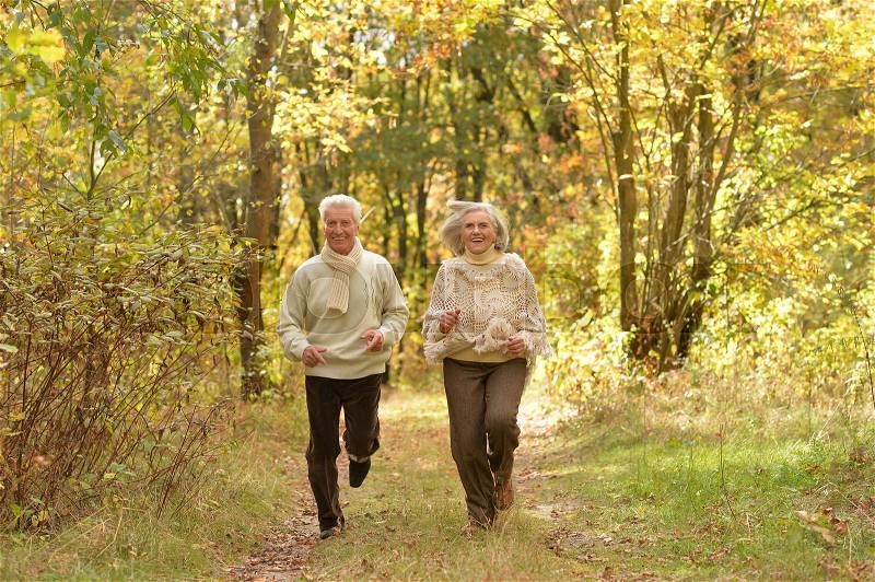 Portrait of beautiful senior couple running in the park, stock photo