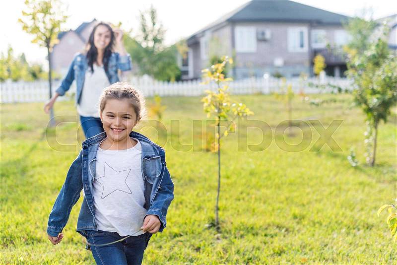 Happy mother and daughter playing catch-up on beautiful garden, stock photo