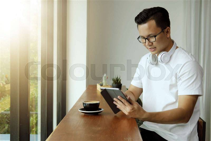 Digital business or shopping online concept. Young asian man using digital tablet at coffee shop, stock photo
