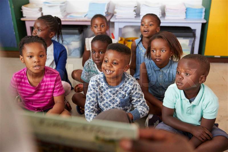 Teacher reading book to elementary school children in class, stock photo