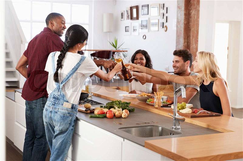 Friends Prepare And Serve Food For Dinner Party At Home Together, stock photo