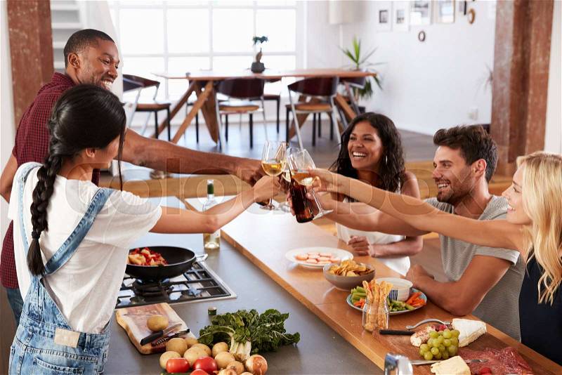 Friends Prepare And Serve Food For Dinner Party At Home Together, stock photo
