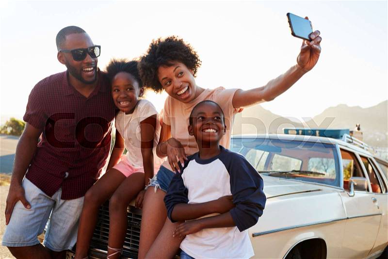 Family Posing For Selfie Next To Car Packed For Road Trip, stock photo