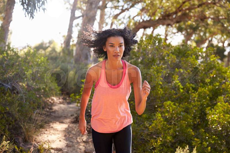 Young black woman jogging in a forest, close up, stock photo