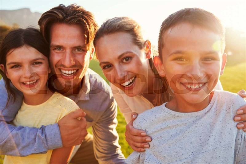 Portrait of happy white family embracing outdoors, backlit, stock photo