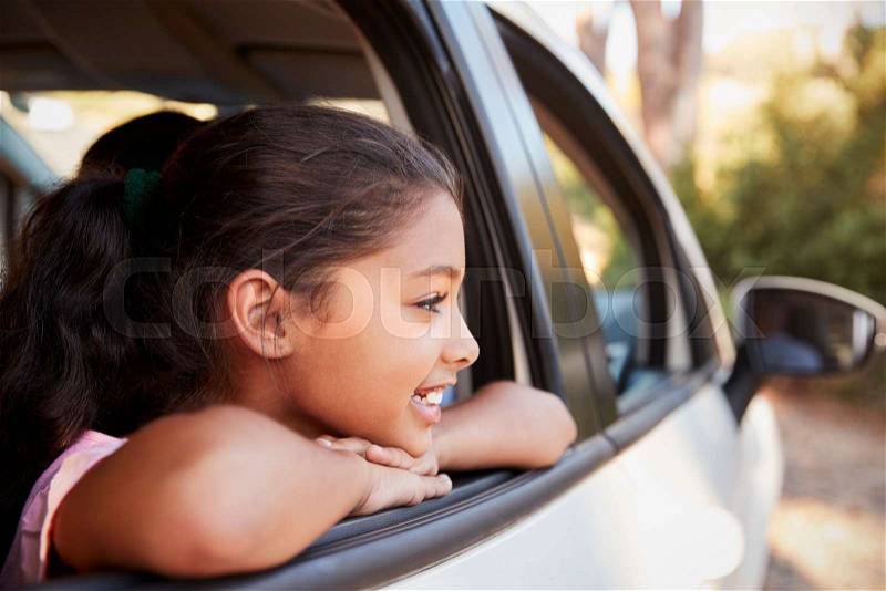 Young black girl looking out of car window smiling, side view, stock photo