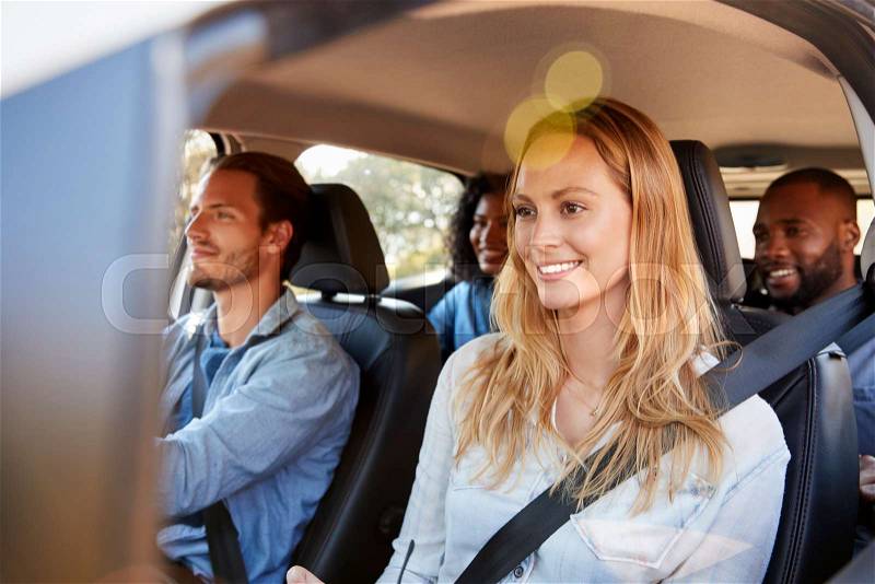 Four happy adult friends in a car on a road trip, stock photo
