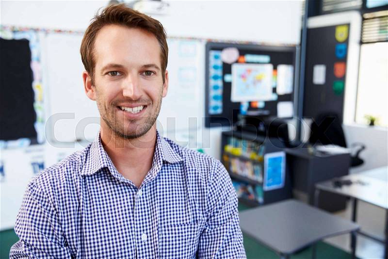 Young white male teacher in school classroom, close up, stock photo