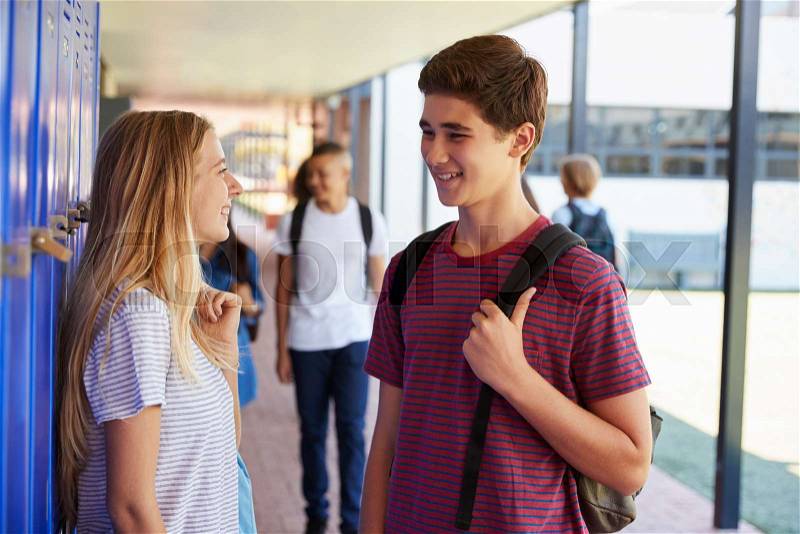 Two friends talking in school corridor at break time, stock photo