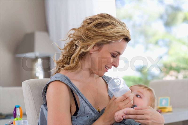 Mother bottle feeds baby, stock photo