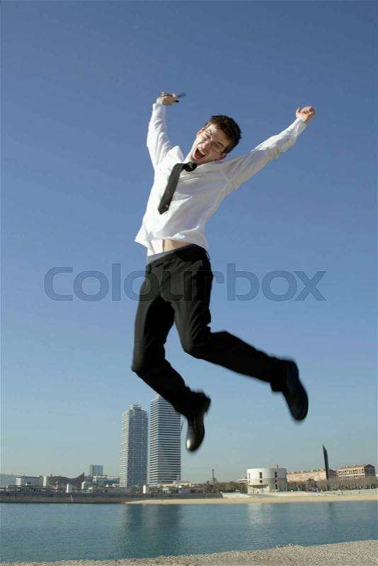 Business man jumping by seafront, stock photo