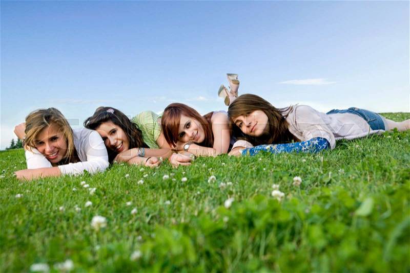 Four teen girls portrait laying on grass, stock photo