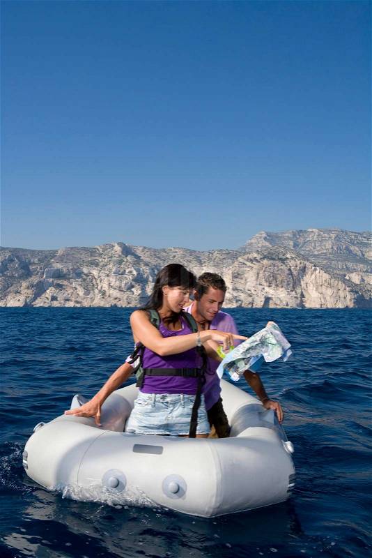 Couple with map on dingy boat, stock photo
