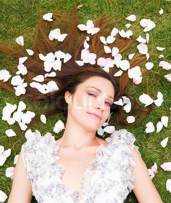 Woman surrounded with rose pedals, stock photo
