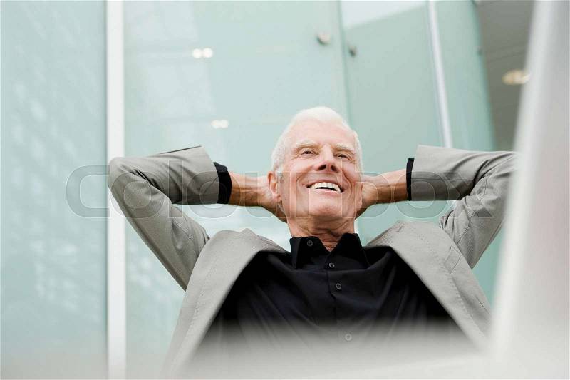 Older man leaning back in a chair, stock photo