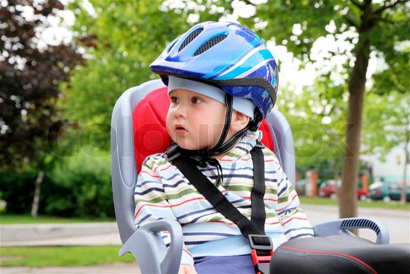 Child sitting by bicycle in crash helmet, stock photo