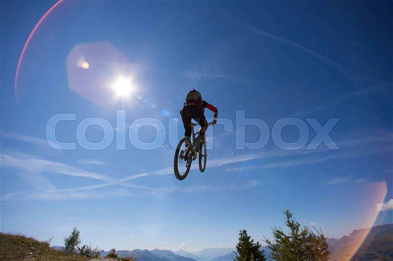 Mountain biker jumping over head, stock photo