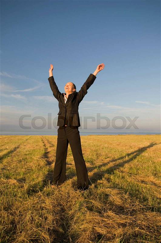 Business woman in a field with arms up, stock photo