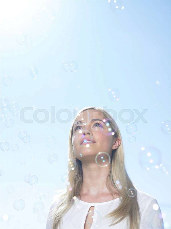 Girl looking at sky with bubbles, stock photo