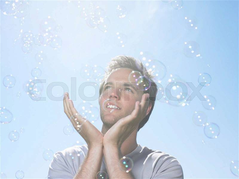 Man in sun holding bubbles, stock photo