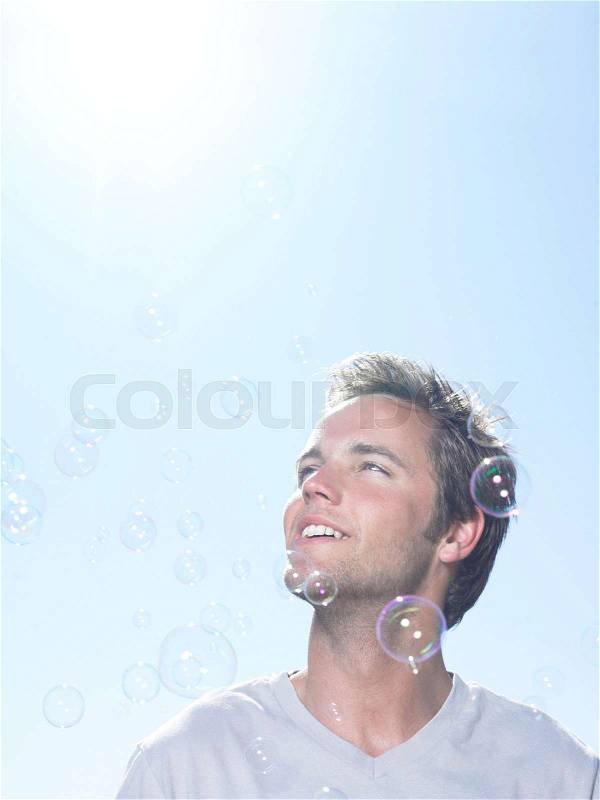 Man in sun looking at bubbles, stock photo