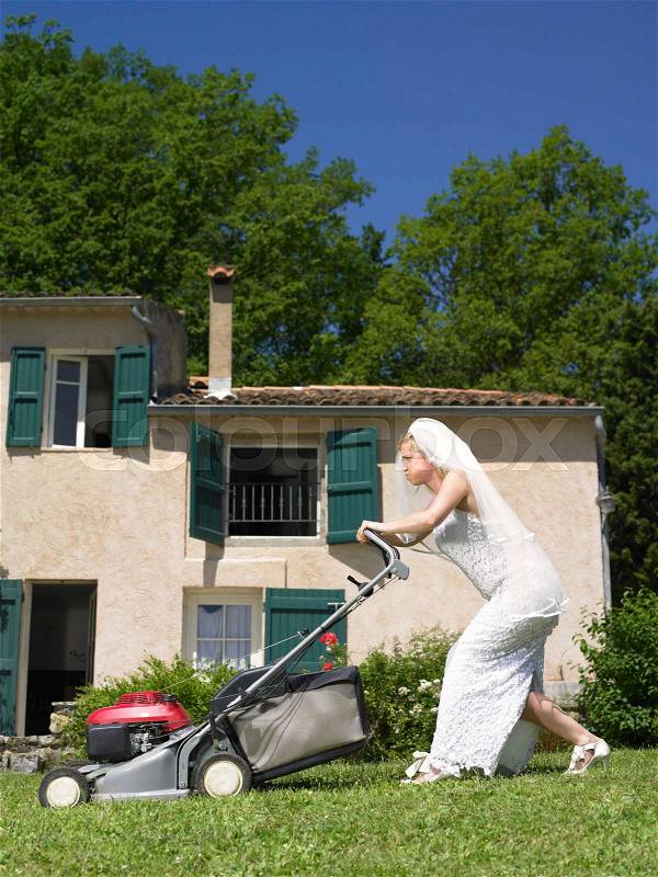 Bride trying to mow lawn, stock photo