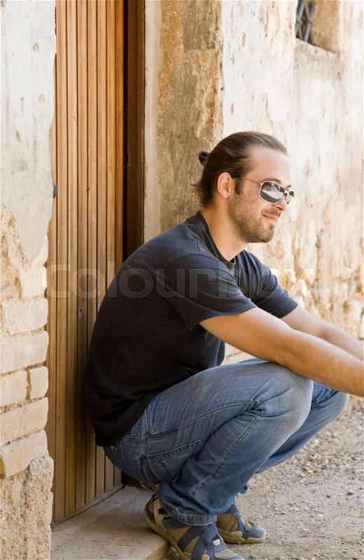 Man crouch down by a doorway, stock photo