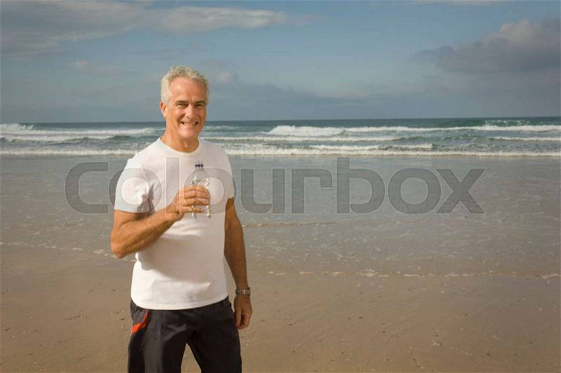 Male drinking water on a beach, stock photo