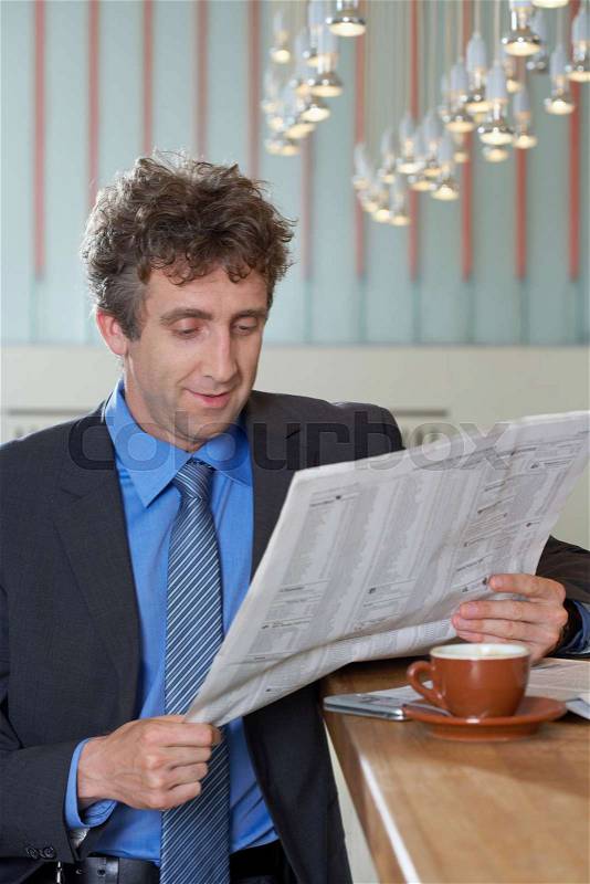 Businessman at bar reading paper, smile, stock photo