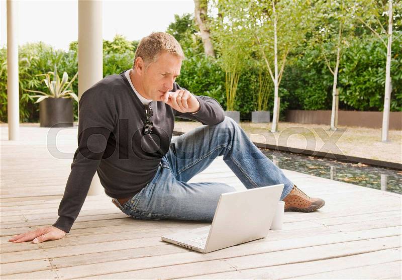 Businessman looking at laptop outside, stock photo