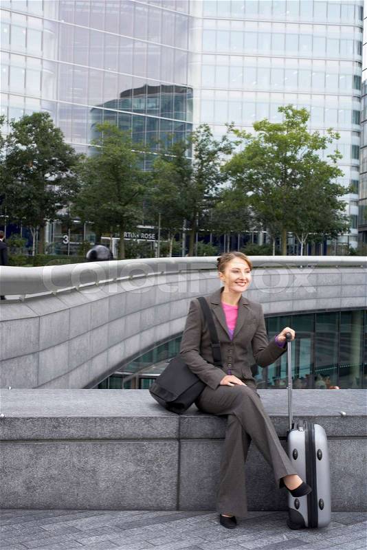 Business woman sitting with luggage, stock photo