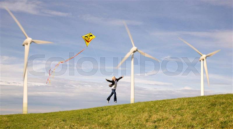 Man jumping with kite at Wind Turbines, stock photo