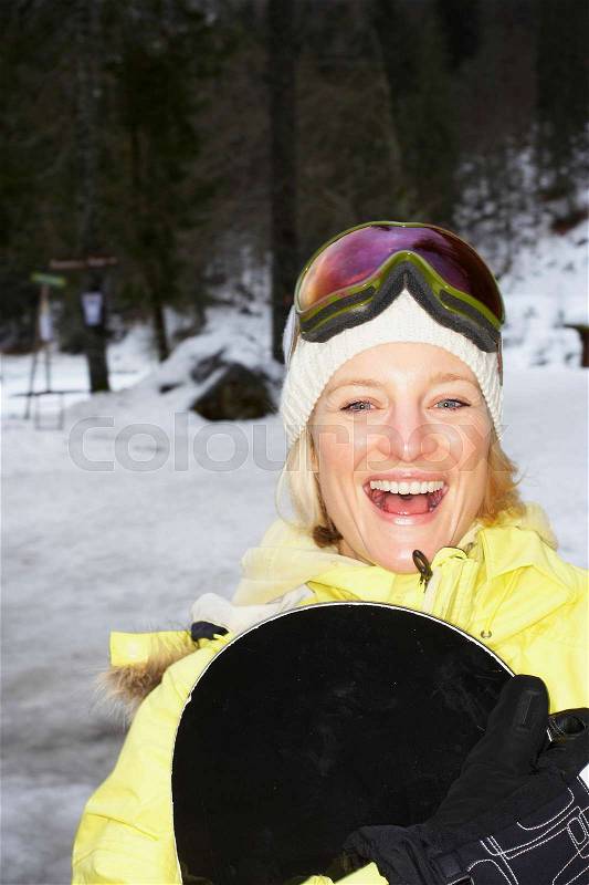 Laughing woman holding snowboard, stock photo
