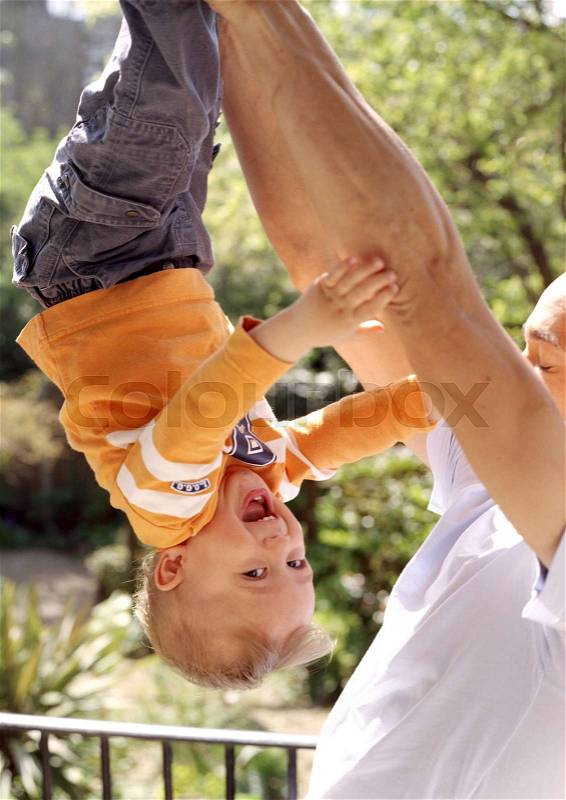 Father holding Son upside down, stock photo
