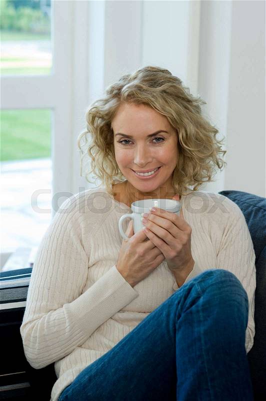 Woman on sofa with cup/mug, stock photo