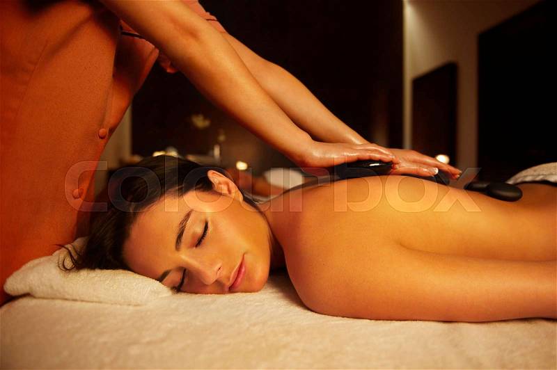 Woman receiving hot stone massage, stock photo