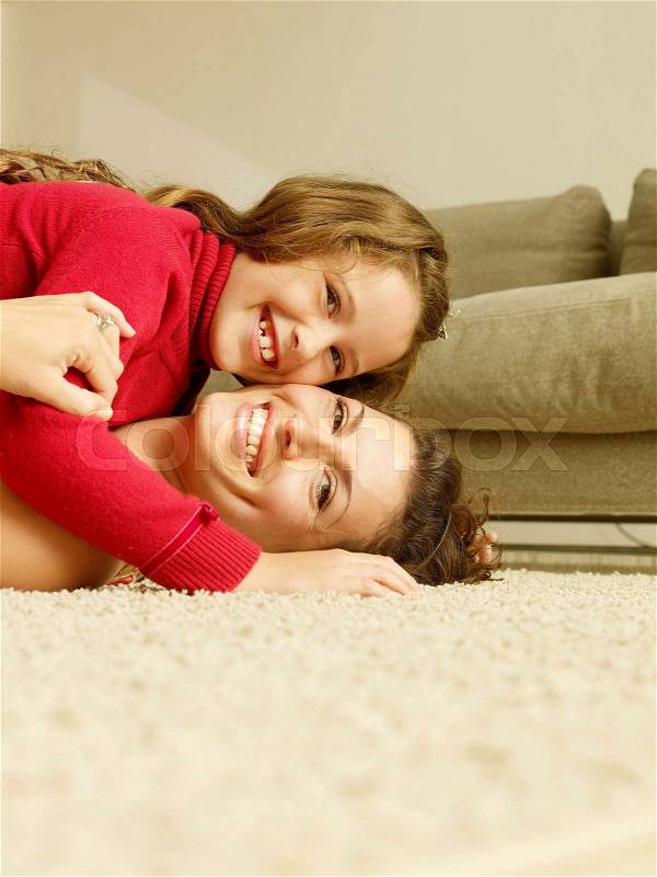 Mom and girl on floor, looking at camera, stock photo