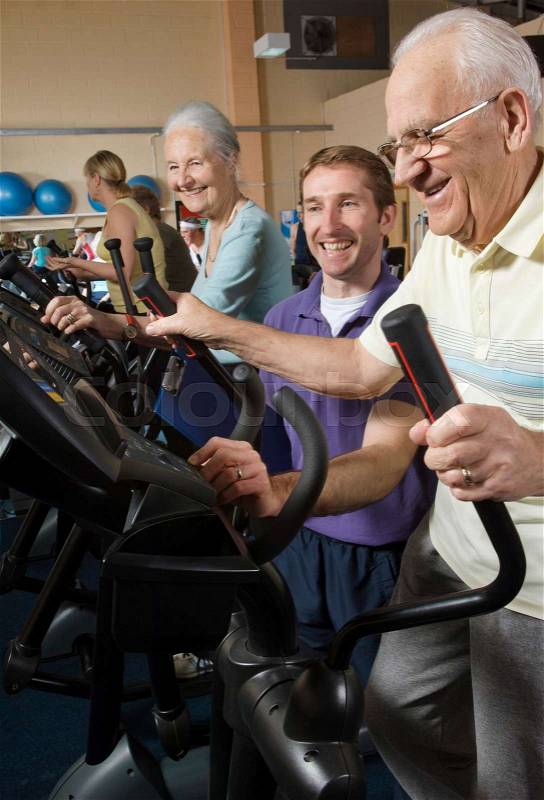 Seniors training at gym with instructor, stock photo