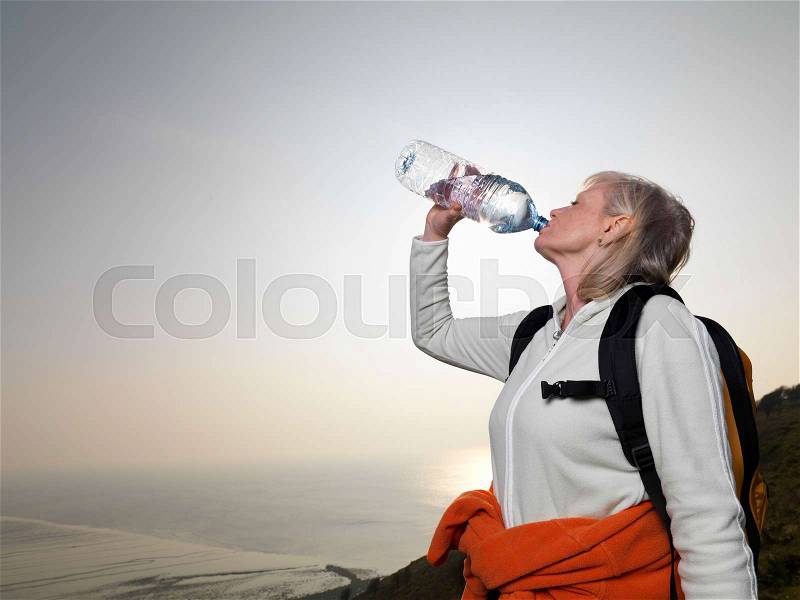 Woman hiking drinking water, stock photo