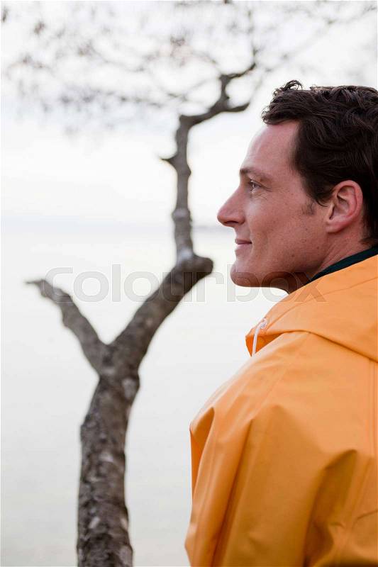 Man in raincoat looking on a lake, stock photo