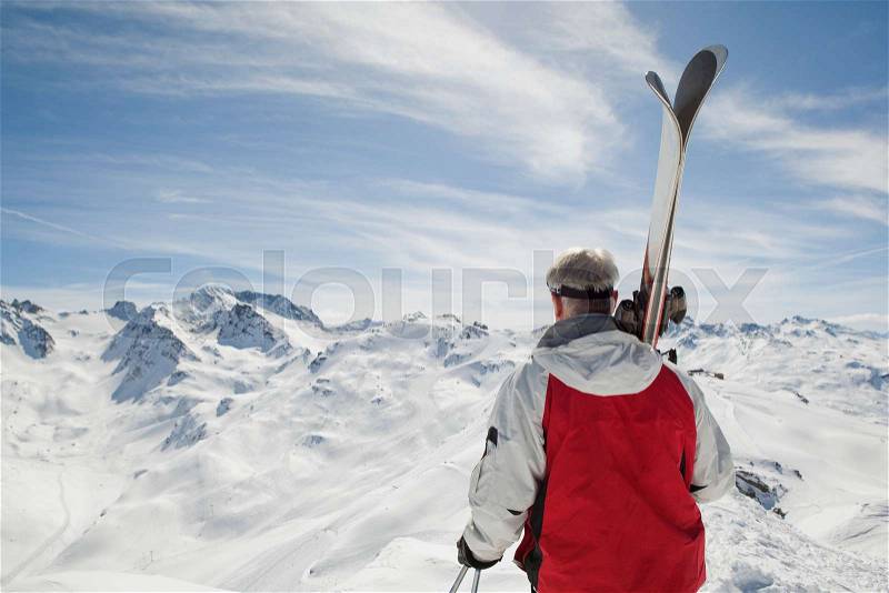 Back view of mature man holding ski\'s, stock photo