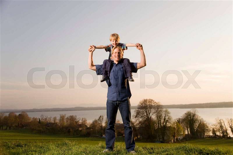 Boy sitting on father's shoulders, stock photo