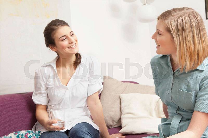 Two women on a sofa, chatting, stock photo