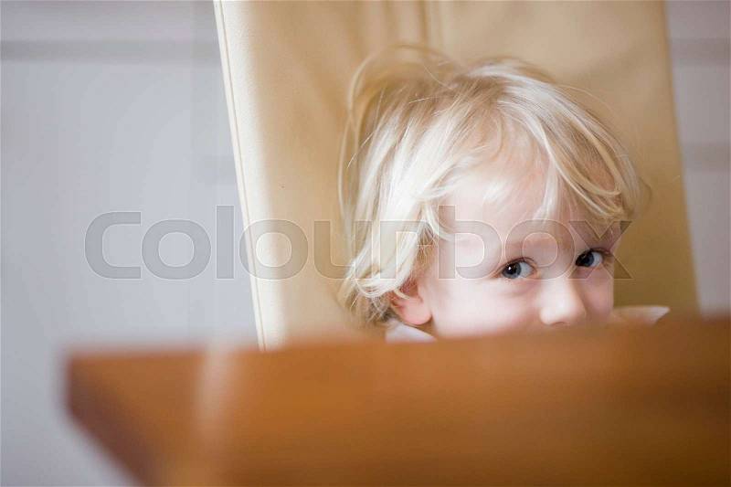 Boy looking over table edge, stock photo