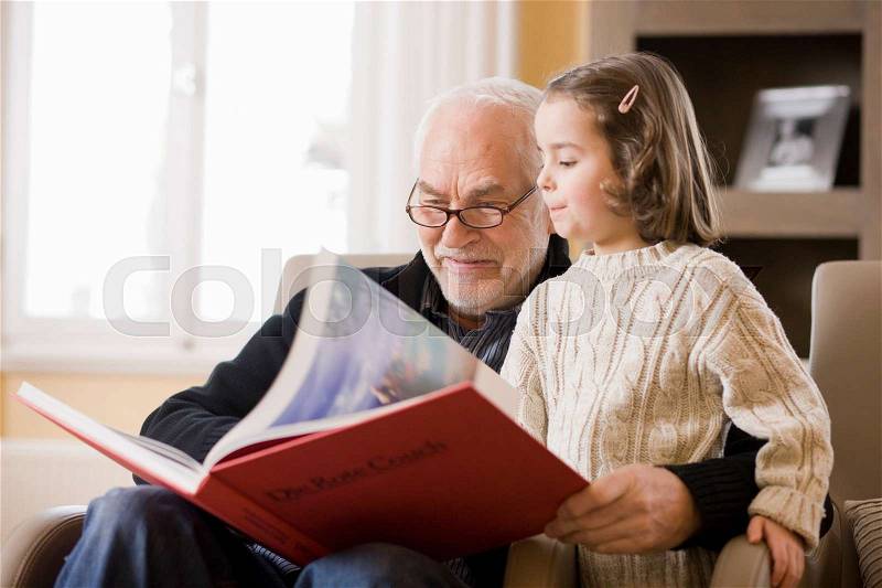 Old man reading book to young girl, stock photo