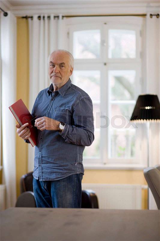 Old man with book looking at viewer, stock photo