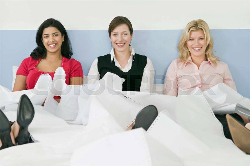 Three female colleagues sitting in bed, stock photo