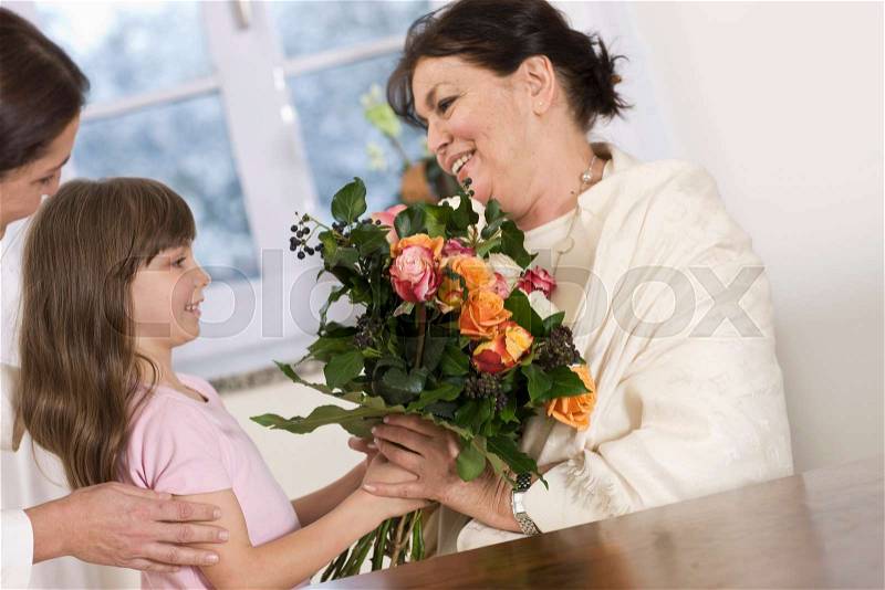 Child giving her grandmother flowers, stock photo