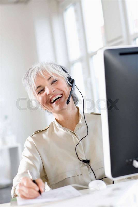 Woman with a headset works in an office, stock photo