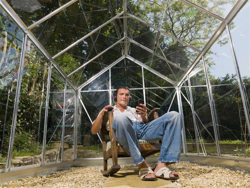 Man in greenhouse with headphones, stock photo